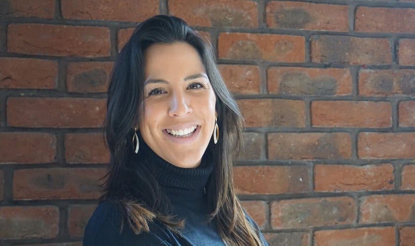 ThinkCyber's Makrting Director Celine Mallet smiling with a brick wall in the background